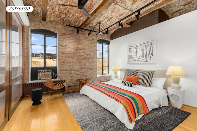 bedroom with multiple windows, brick ceiling, hardwood / wood-style floors, and brick wall