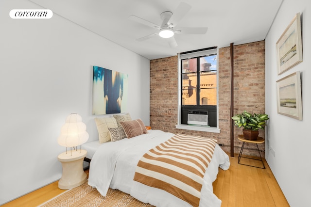 bedroom featuring ceiling fan, brick wall, cooling unit, and hardwood / wood-style floors