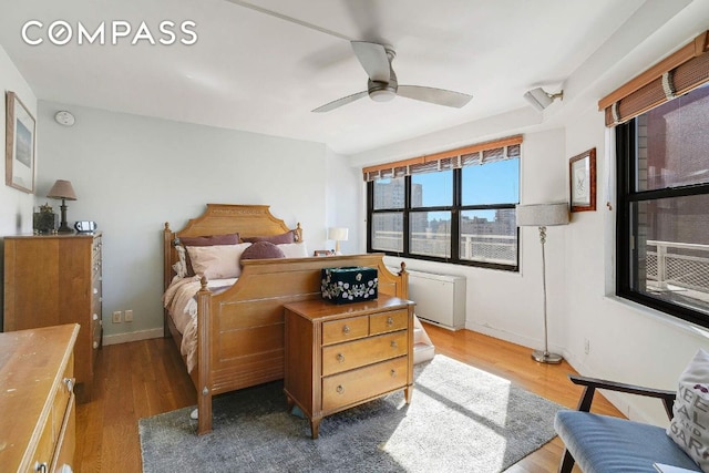 bedroom featuring radiator heating unit, baseboards, ceiling fan, and wood finished floors