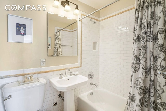 bathroom featuring toilet, shower / bath combo, tile walls, and wainscoting