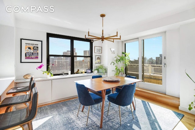 dining area with a city view, a notable chandelier, and light wood-style flooring