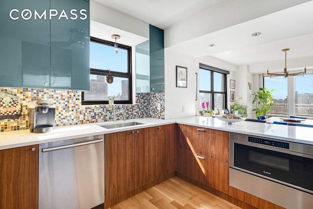 kitchen featuring a sink, brown cabinets, stainless steel dishwasher, and light countertops