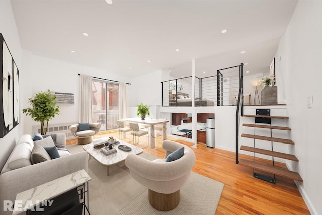 living room featuring light wood-type flooring, baseboards, recessed lighting, and stairs