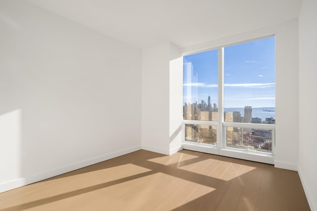 15 Hudson Yards Unit 38C, New York City, NY 10001 - spare room with a view of skyline, wood finished floors, and baseboards
