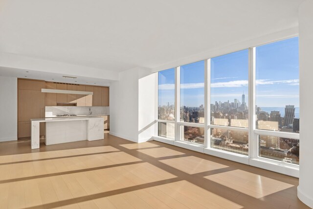 15 Hudson Yards Unit 38C, New York City, NY 10001 - unfurnished living room featuring a view of skyline, light wood-type flooring, baseboards, a wall of windows, and plenty of natural light