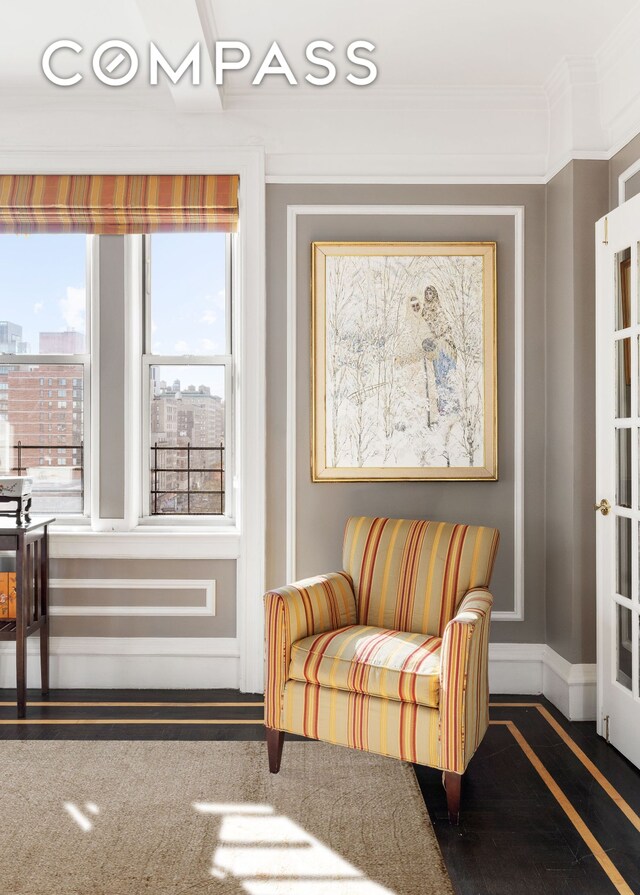 sitting room with a view of city, crown molding, and baseboards