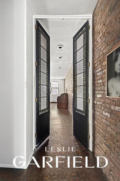 hallway featuring a textured ceiling, brick wall, and baseboards