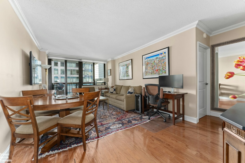 dining area with a textured ceiling, wood finished floors, and ornamental molding