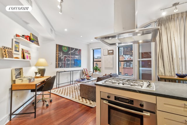 kitchen with track lighting, visible vents, dark wood-type flooring, island range hood, and stainless steel appliances