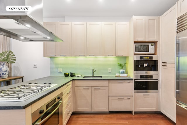 kitchen with under cabinet range hood, stainless steel appliances, a sink, and dark countertops
