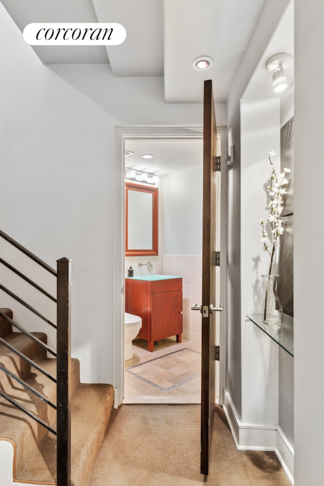 bathroom featuring toilet, vanity, wainscoting, tile walls, and recessed lighting