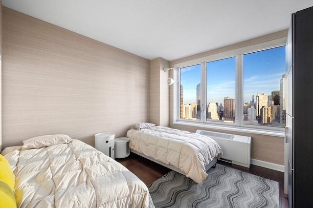 80 Riverside Blvd Unit Ph-1B, New York City, NY 10069 - bedroom featuring radiator heating unit, a skyline view, baseboards, and dark wood finished floors