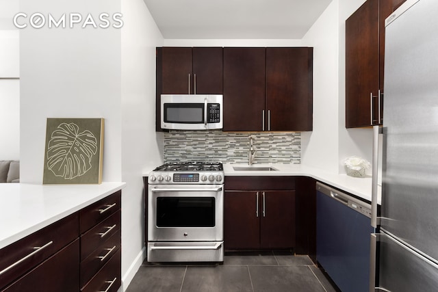 kitchen with a sink, appliances with stainless steel finishes, decorative backsplash, and light countertops