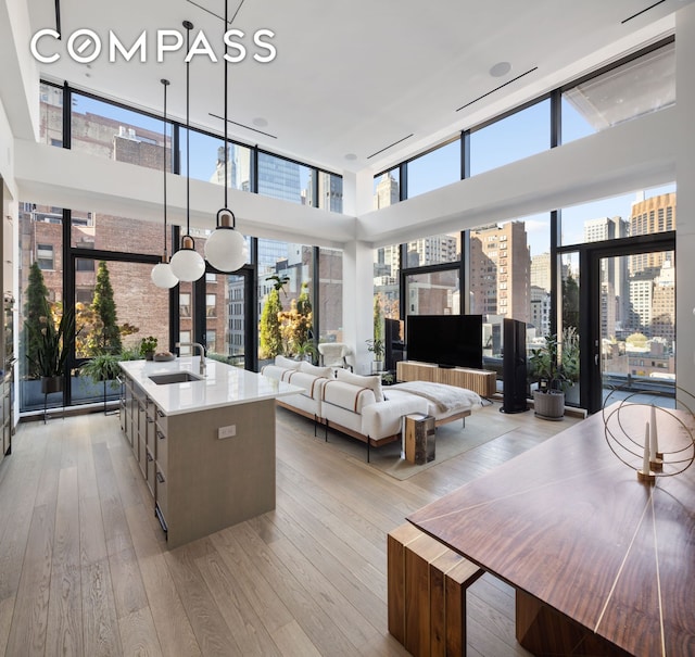 living area with a high ceiling, plenty of natural light, light wood finished floors, and expansive windows