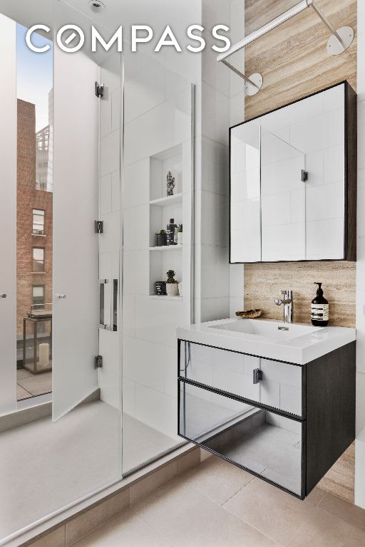 bathroom featuring tile patterned floors, a shower with shower door, and vanity