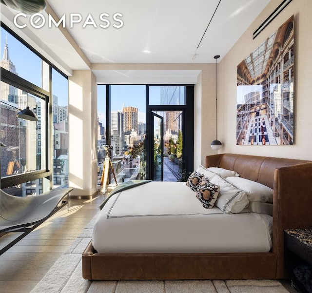 bedroom featuring access to exterior, wood-type flooring, and a wall of windows