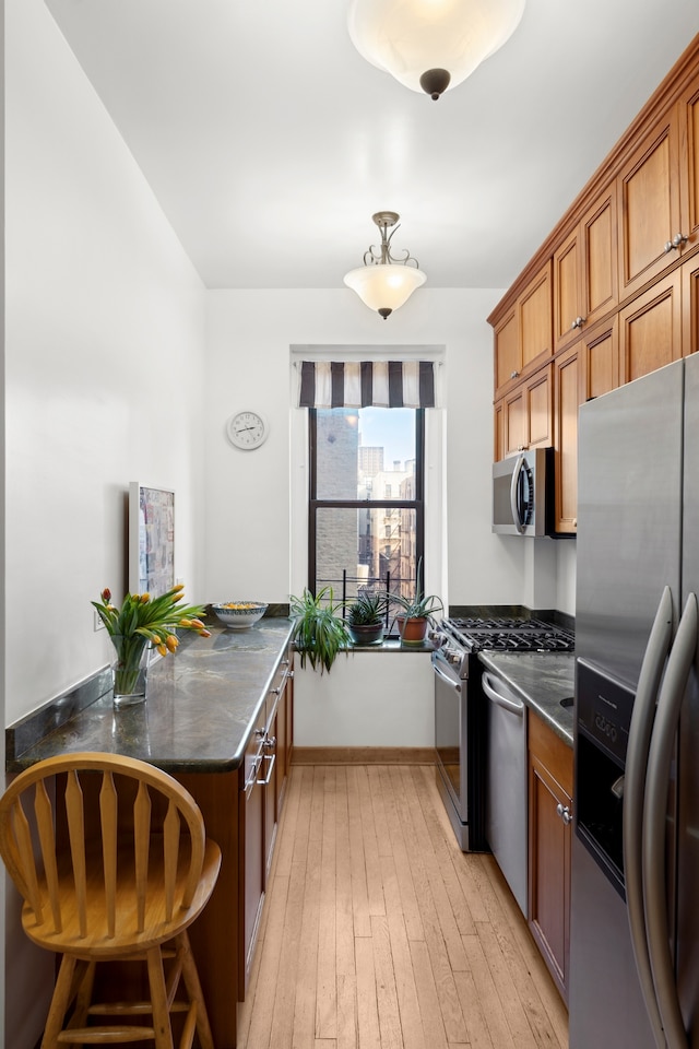 790 Riverside Dr Unit 6-C, New York City, NY 10032 - kitchen featuring stainless steel appliances, a peninsula, dark countertops, and brown cabinets