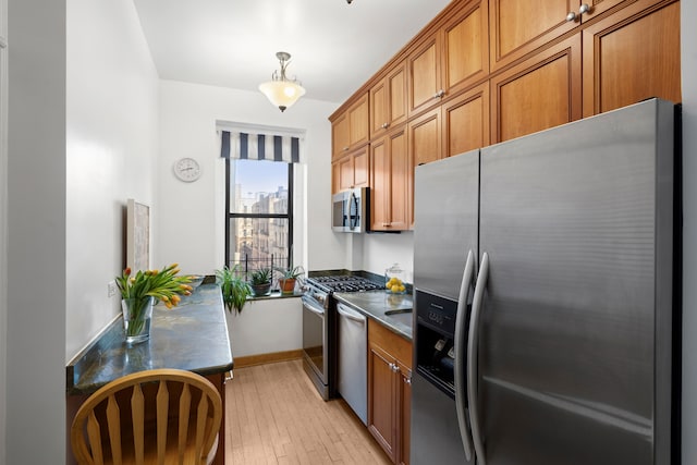 790 Riverside Dr Unit 6-C, New York City, NY 10032 - kitchen featuring appliances with stainless steel finishes, brown cabinetry, dark countertops, and light wood-style flooring