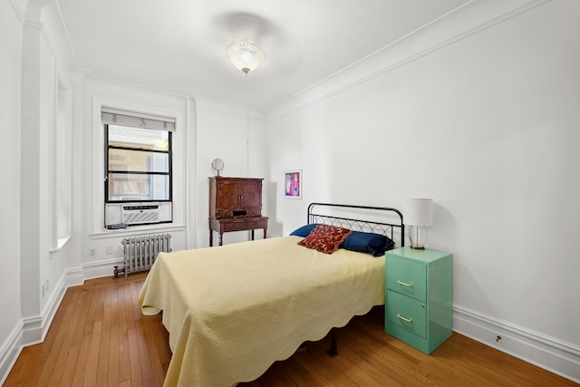 bedroom with radiator, hardwood / wood-style flooring, ornamental molding, baseboards, and cooling unit