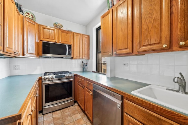 kitchen featuring tasteful backsplash, light countertops, appliances with stainless steel finishes, brown cabinetry, and a sink