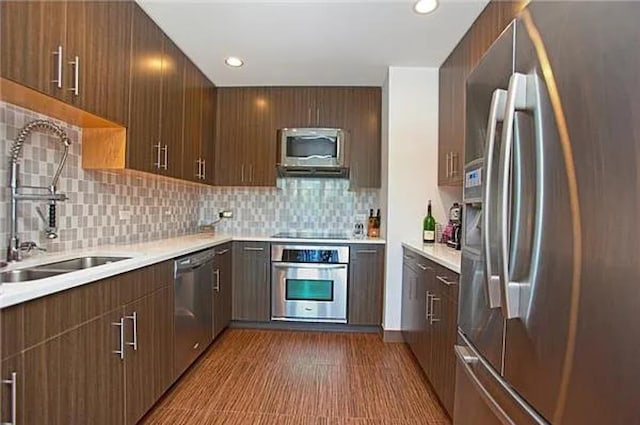 kitchen with light countertops, appliances with stainless steel finishes, a sink, and decorative backsplash