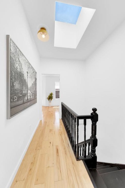 hallway with hardwood / wood-style flooring and a skylight