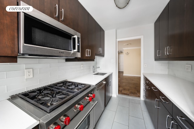 kitchen featuring stainless steel appliances, light countertops, a sink, and dark brown cabinets