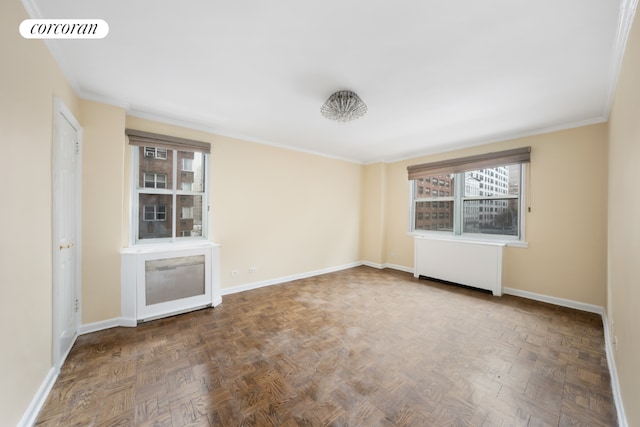 spare room with radiator, baseboards, visible vents, and crown molding