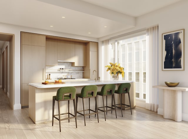 kitchen featuring a breakfast bar, light hardwood / wood-style flooring, sink, tasteful backsplash, and light brown cabinets