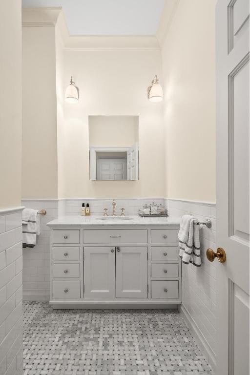 bathroom featuring tile walls, crown molding, and wainscoting