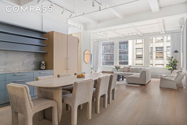 dining area with beam ceiling, rail lighting, and light wood-style floors