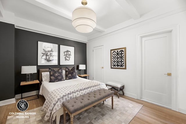 bedroom featuring baseboards, beamed ceiling, and wood finished floors