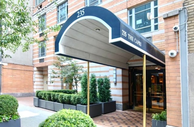property entrance with brick siding and a security system
