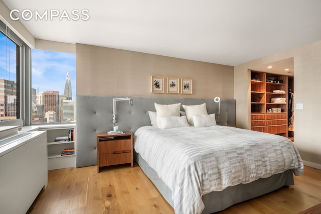 bedroom with light wood finished floors and a city view