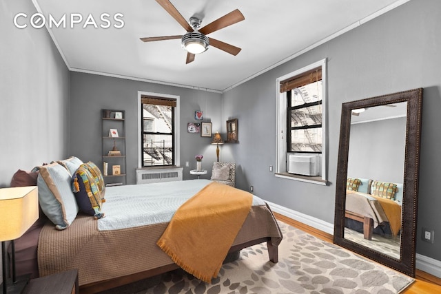 bedroom with baseboards, radiator heating unit, wood finished floors, and crown molding