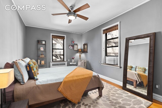 bedroom with crown molding, radiator heating unit, wood finished floors, and baseboards