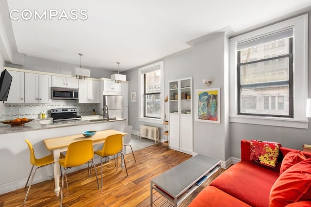 interior space with radiator heating unit, light wood-style flooring, and baseboards