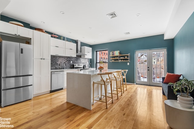 kitchen featuring a kitchen island, white cabinetry, light countertops, stainless steel appliances, and french doors