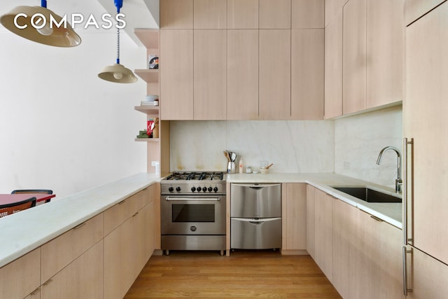 kitchen featuring light brown cabinetry, appliances with stainless steel finishes, and a sink