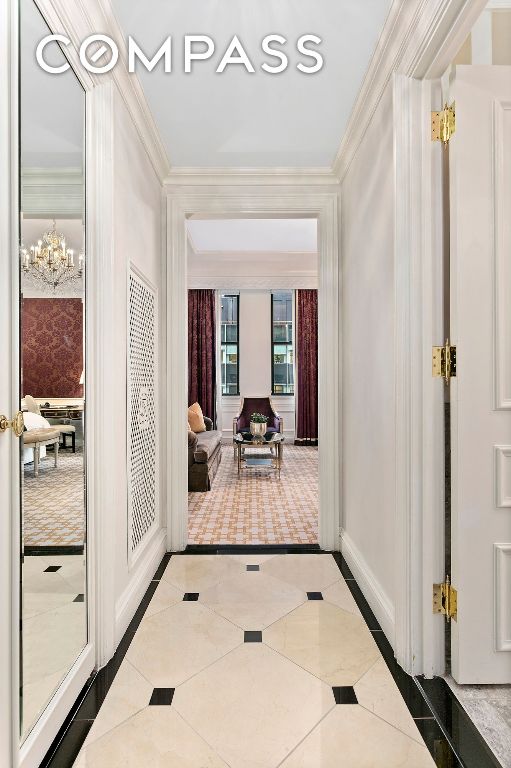 interior space with a chandelier, tile patterned flooring, crown molding, and baseboards