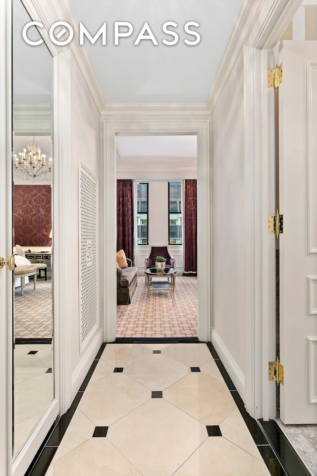 interior space featuring baseboards, a chandelier, and crown molding