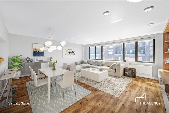 dining room featuring a chandelier, radiator heating unit, and wood finished floors