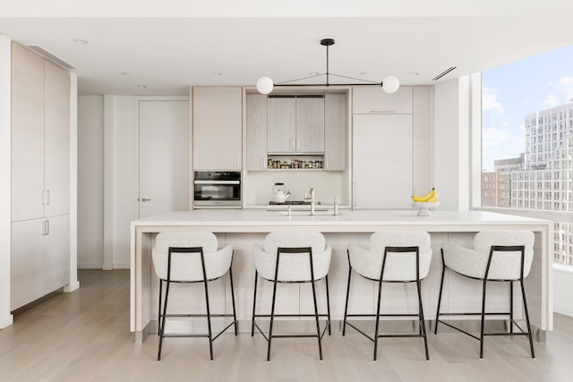 kitchen with modern cabinets, oven, light countertops, light wood-type flooring, and a sink