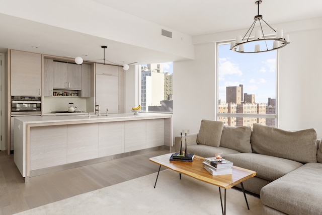 living area featuring a view of city, an inviting chandelier, visible vents, and light wood-style floors