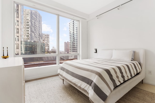 bedroom with a view of city, baseboards, and track lighting