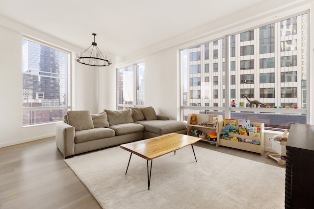 living room featuring a healthy amount of sunlight, baseboards, wood finished floors, and a chandelier