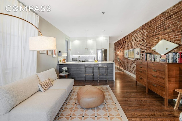 living room with dark wood-style floors and brick wall