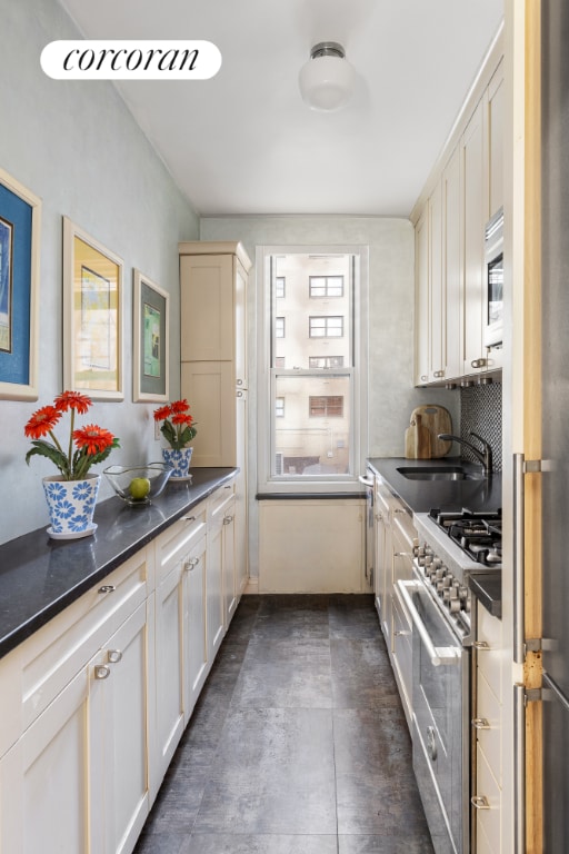 kitchen with a sink, white cabinets, appliances with stainless steel finishes, decorative backsplash, and dark countertops