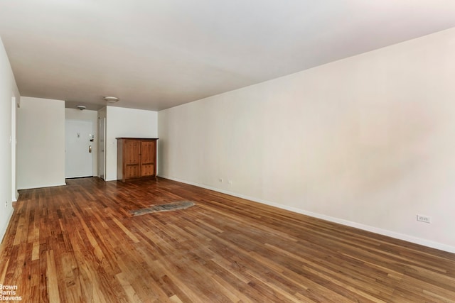 unfurnished living room featuring dark wood-type flooring and baseboards