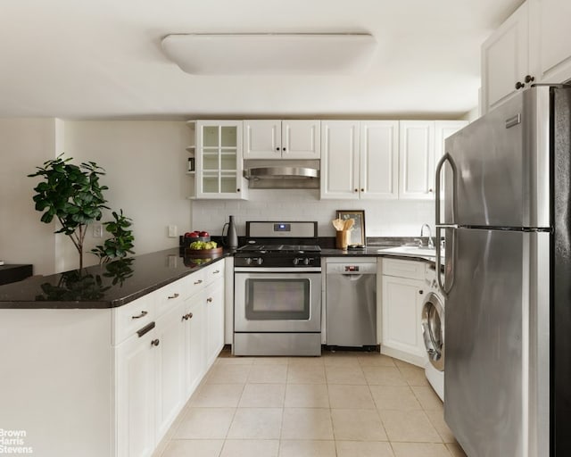 kitchen with under cabinet range hood, appliances with stainless steel finishes, glass insert cabinets, and white cabinetry